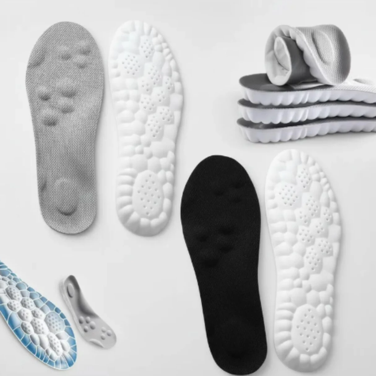 Plantillas deportivas acolchadas en blanco, negro y gris con base antideslizante; vista superior mostrando textura de apoyo y diseño ergonómico.