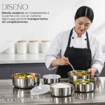 Chef mujer con delantal negro sirve ensalada en bowls de acero inoxidable sobre mesa metálica, acompañados de tapas blancas y contenedores cerrados.