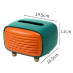 Dispensador de servilletas estilo radio retro en verde y naranja, con medidas de 19.5 x 16.5 x 11 cm, diseño hermético para proteger pañuelos de la humedad.
