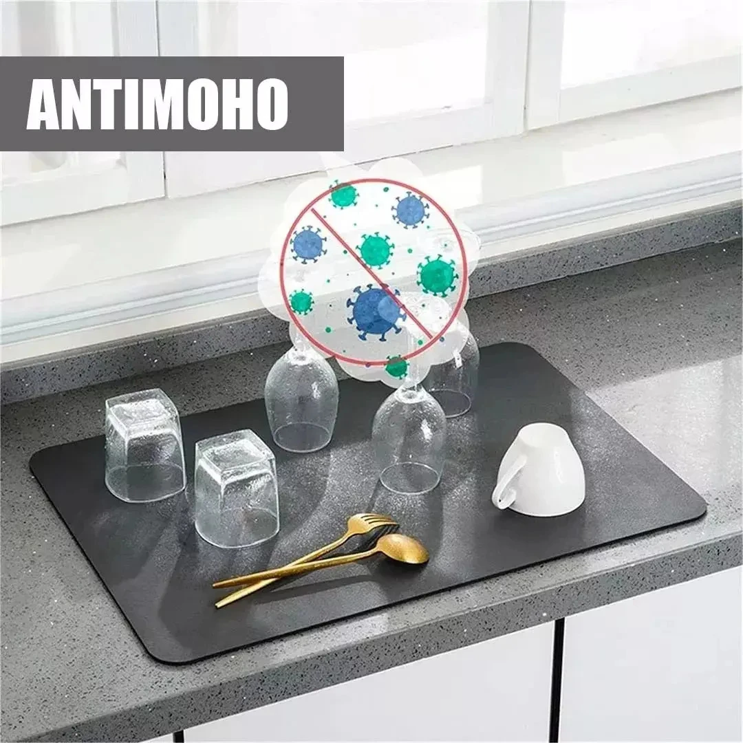 Tapete absorbente negro en cocina, con vasos, cuchara dorada y taza blanca; incluye de protección antiviral.