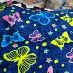 Cobija térmica para cama doble con estampado de mariposas multicolores sobre fondo azul oscuro, textura suave y diseño vibrante.