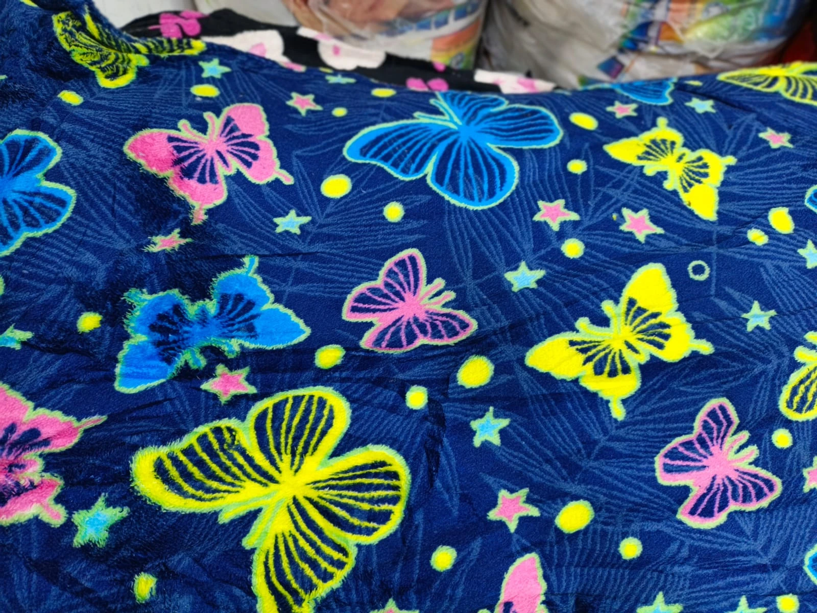 Cobija térmica para cama doble con estampado de mariposas multicolores sobre fondo azul oscuro, textura suave y diseño vibrante.