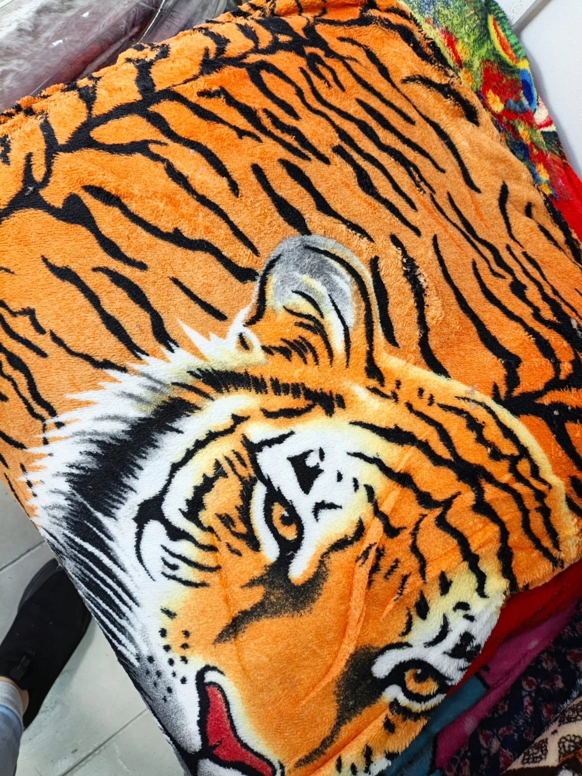 Cobija térmica de felpa con estampado realista de tigre en tonos naranjas y negros, vista frontal mostrando cabeza y patas.