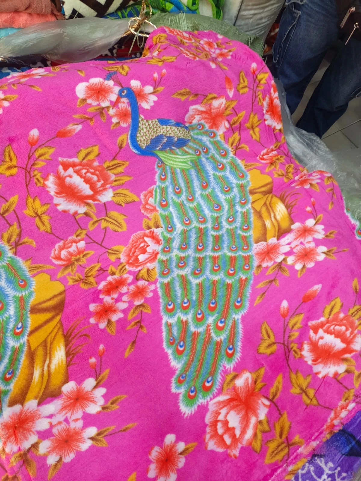 Cobija térmica rosa con diseño de pavo real y flores, vista frontal mostrando textura suave y estampado completo.
