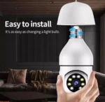 Cámara bombillo blanca con base de LED y lente central, montada en mano sobre sala de estar oscura.