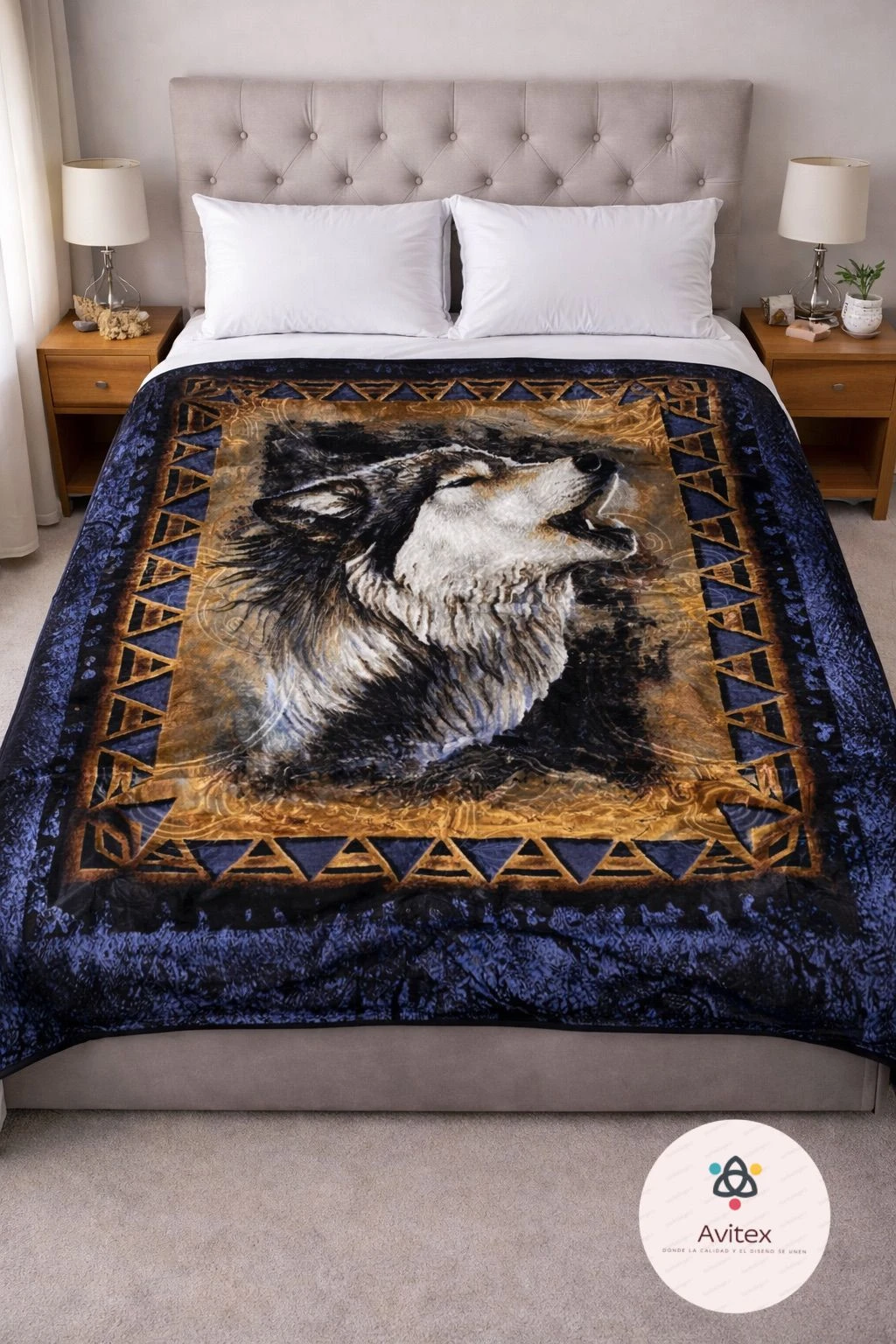 Colcha con diseño de lobo aullando sobre fondo azul oscuro y dorado, bordada con patrones geométricos, colocada sobre cama con cabecero tapizado y almohadas blancas.