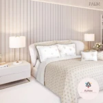 Edredón acolchado doble faz en tono crema con estampado floral, sobre cama doble en habitación moderna con mesitas de noche y lámparas.