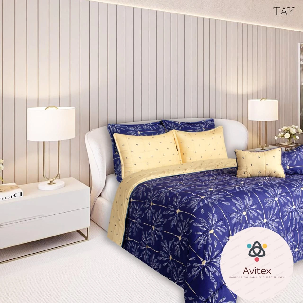 Edredón acolchado doble faz en azul con estampado floral y cojines amarillos sobre cama blanca, en habitación moderna con lámparas y pared vertical.