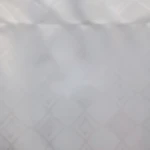 Cortina en velo blanca con sutil patrón geométrico de rombos entrelazados, tela ligera que filtra suavemente la luz natural.