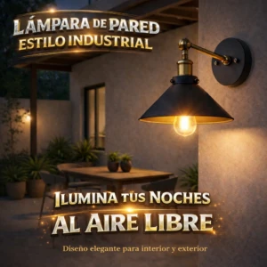 Lámpara de pared industrial en color negro mate con acabado metálico dorado, montada en pared exterior de concreto, iluminando patio con mesa y plantas; bombilla E27 visible.