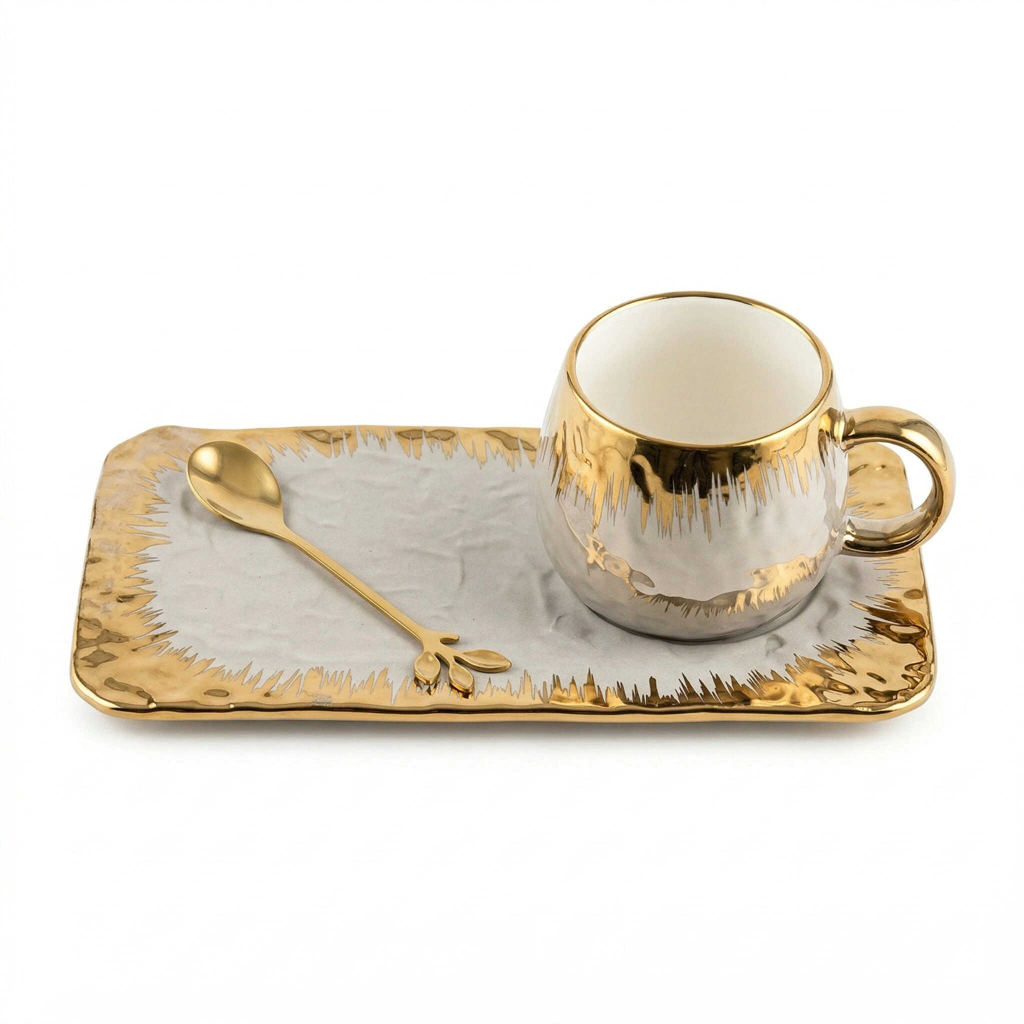 Taza y bandeja de cerámica con acabado dorado y textura orgánica, acompañadas de cuchara, sobre fondo blanco.