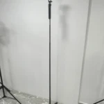 Trípode P205 negro con brazo extensible y base de tres patas, montado sobre piso de baldosas blancas con vetas grises.