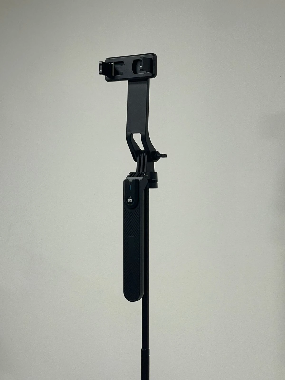 Trípode P205 negro con brazo extensible y soporte para smartphone, mostrando control Bluetooth y mango ergonómico.