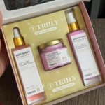 Kit de cuidado corporal Truly con aceite después de afeitado, crema corporal y aceite corporal en caja rosa.
