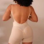 Faja moldeadora color crema con espalda descubierta, vista posterior en modelo con cabello rizado.