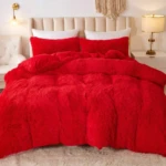 Edredón térmico peludo rojo sobre cama doble con cabecero beige y cojines blancos, textura suave y voluminosa.