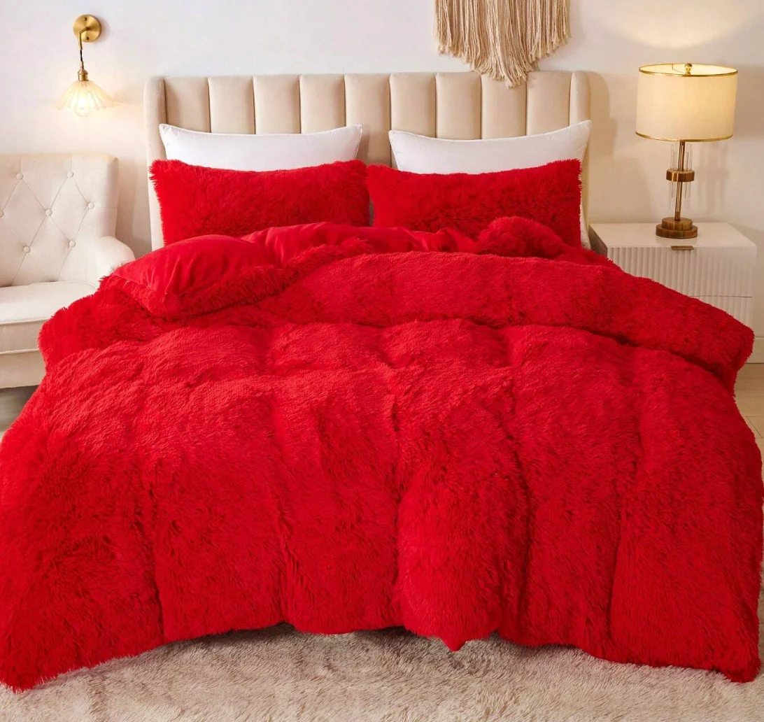 Edredón térmico peludo rojo sobre cama doble con cabecero beige y cojines blancos, textura suave y voluminosa.