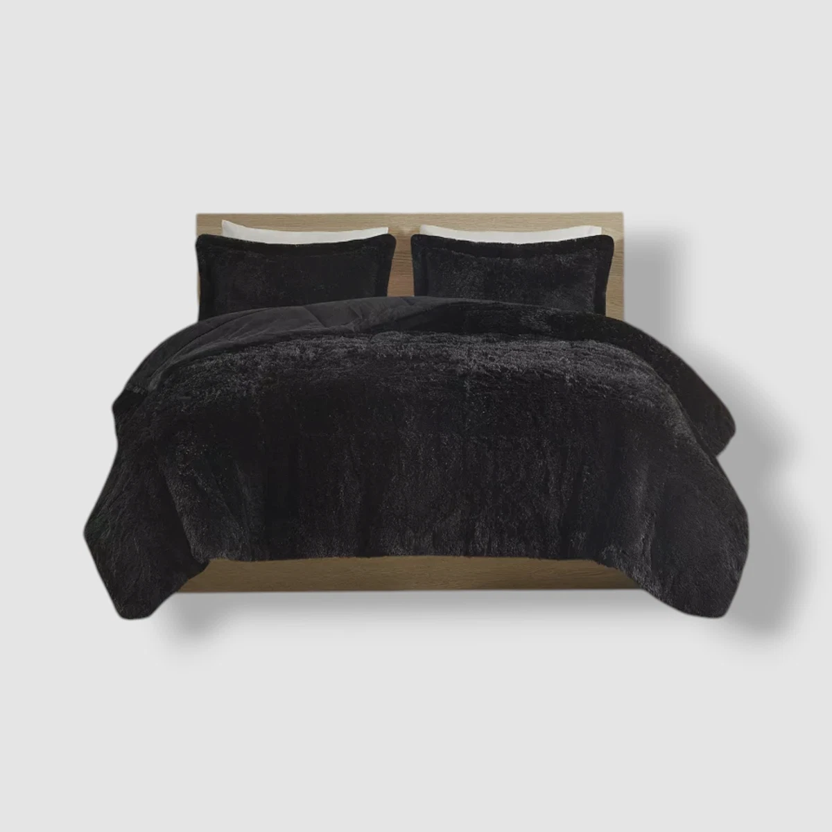 Edredón térmico peludo negro para cama doble, con dos almohadas y cabecero de madera clara.