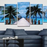 Reloj políptico de cinco paneles con paisaje marino, palmeras y pasarela de madera sobre fondo azul claro. Incluye esfera horaria integrada en el panel derecho.