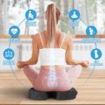 Mujer sentada en posición de loto sobre almohada ergonómica negra con soporte lumbar, ilustrando alivio de dolor de espalda y mejora postural.