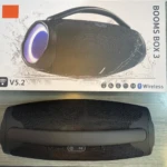 Parlante portátil negro con asa, caja de presentación y detalles en azul. Modelo Booms Box 3, resistente al agua, con luces LED y conectividad Bluetooth.