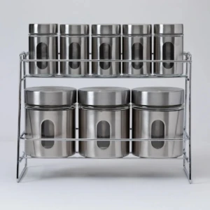 Organizador de cocina metálico con 8 frascos de vidrio y tapa de acero inoxidable, dispuestos en dos niveles para almacenamiento de especias.
