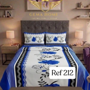 Juego de sábanas de polialgodón 800 hilos con planchado permanente, color azul y blanco, con diseño floral en el centro y bordes decorativos, sobre cama con cabecero gris.
