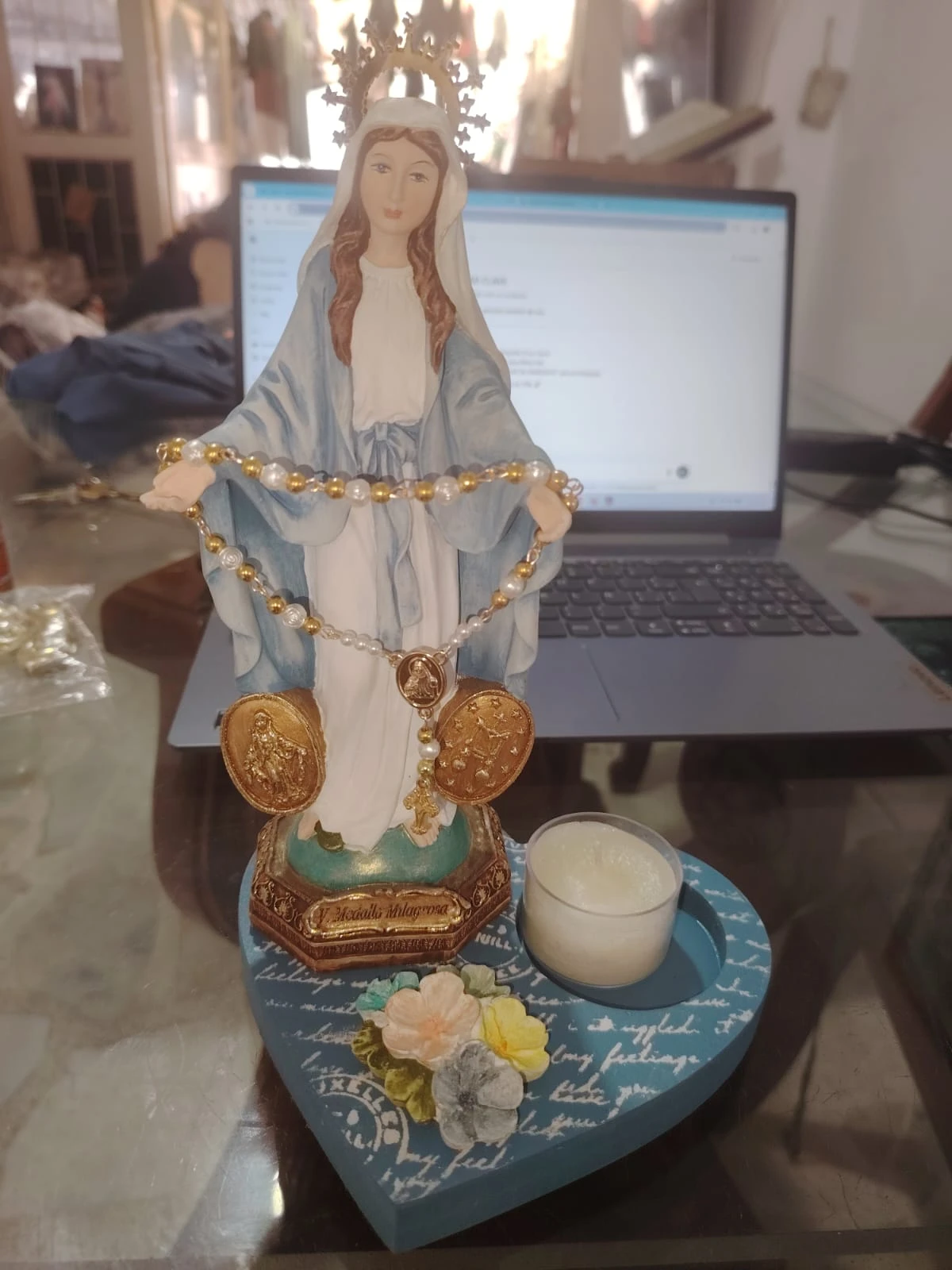 Virgen Milagrosa de resina con base corazón azul, veladora blanca y rosario dorado, ideal para altar o decoración religiosa en hogar.