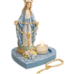 Estátua de la Virgen Milagrosa con base en forma de corazón azul, veladora encendida y rosario de perlas blancas con crucifijo dorado.