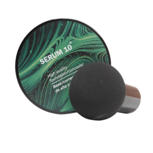 Paleta redonda con diseño verde ondulado y aplicador de esponja negra, base maquillaje alta cobertura para unificar tono de piel y ocultar imperfecciones.