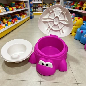 Orinal para bebé en forma de tortuga fucsia con tapa blanca y asiento desmontable, ubicado en tienda de juguetes.