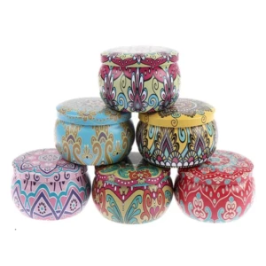Set de tres velas aromáticas de soya en recipientes metálicos decorados con patrones étnicos multicolores, apilados en forma de pirámide sobre fondo blanco.