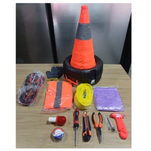Kit de emergencia para carretera con cono naranja, guantes, chaleco reflectante, cinta amarilla, manta térmica, herramientas manuales y botiquín básico sobre mesa.