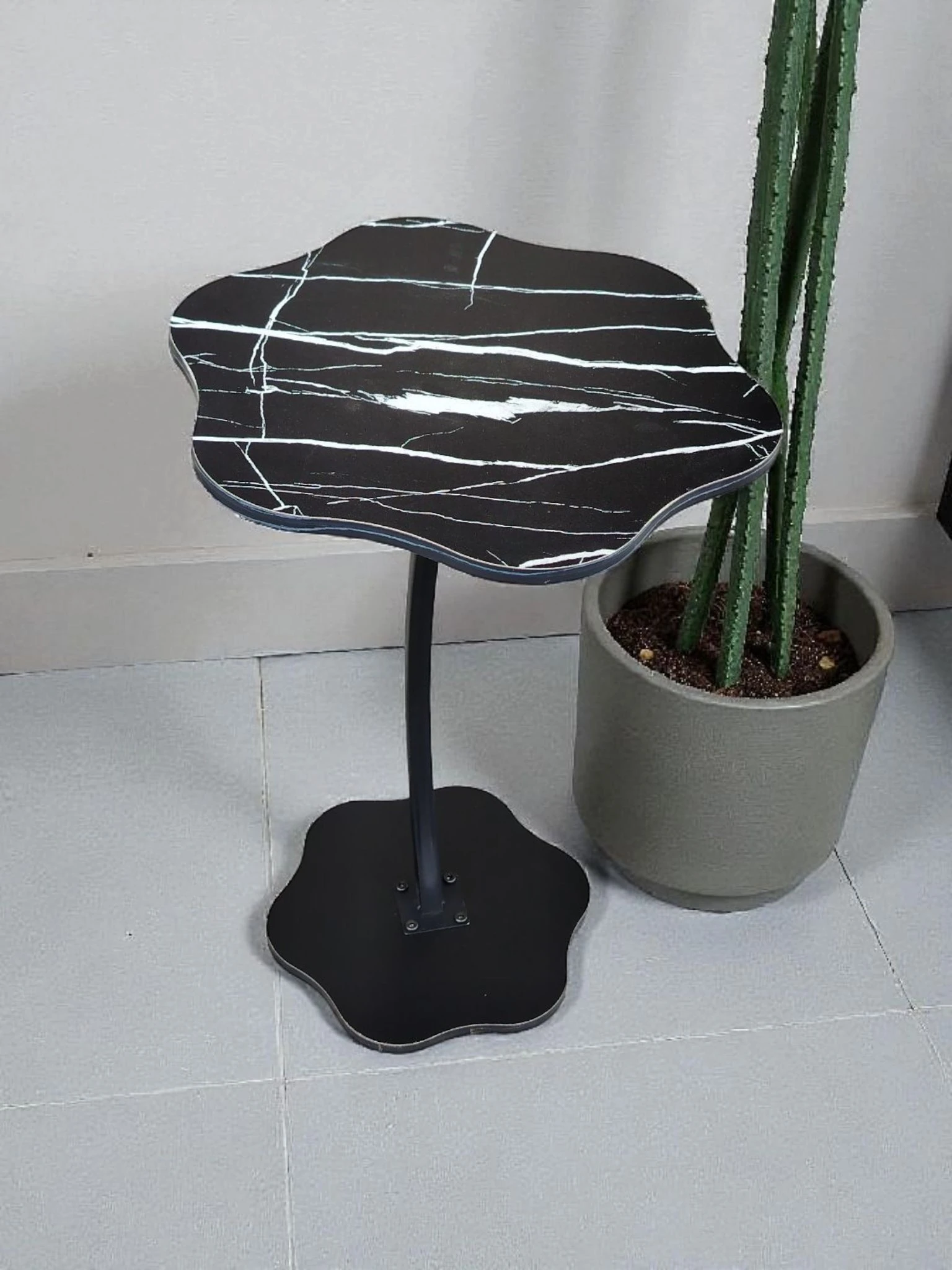 Mesa auxiliar Flower Vintage con superficie de mármol negro y vetas blancas, base metálica negra y diseño orgánico en forma de flor.