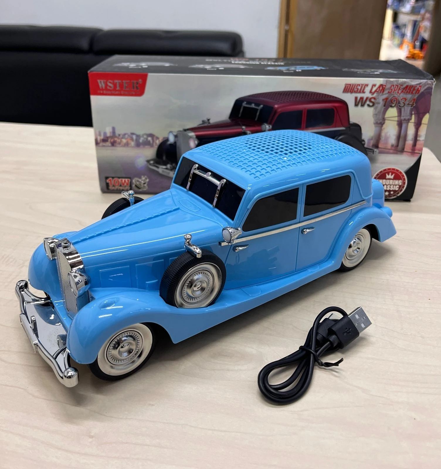 Carro parlante azul estilo Mercedes-Benz 770 con luces LED, reproductor de música y cable USB incluido, sobre superficie clara con caja original al fondo.