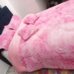 Edredón térmico peludo rosa sobre cama con cabecero azul, textura suave y voluminosa, ideal para invierno.