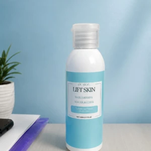 Botella de crema reafirmante Lift Skin en tono azul claro, con etiqueta blanca y tapa transparente, sobre superficie clara junto a cuaderno y planta.