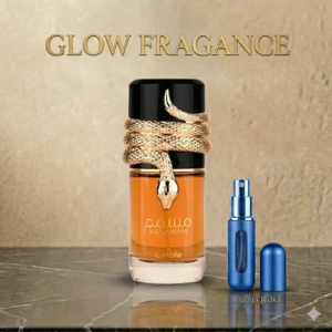 Perfume Musamam Café para caballero en frasco de vidrio con líquido ámbar, tapa negra y serpiente dorada enrollada. Incluye atomizador azul metálico y tapa separada, sobre superficie de mármol.