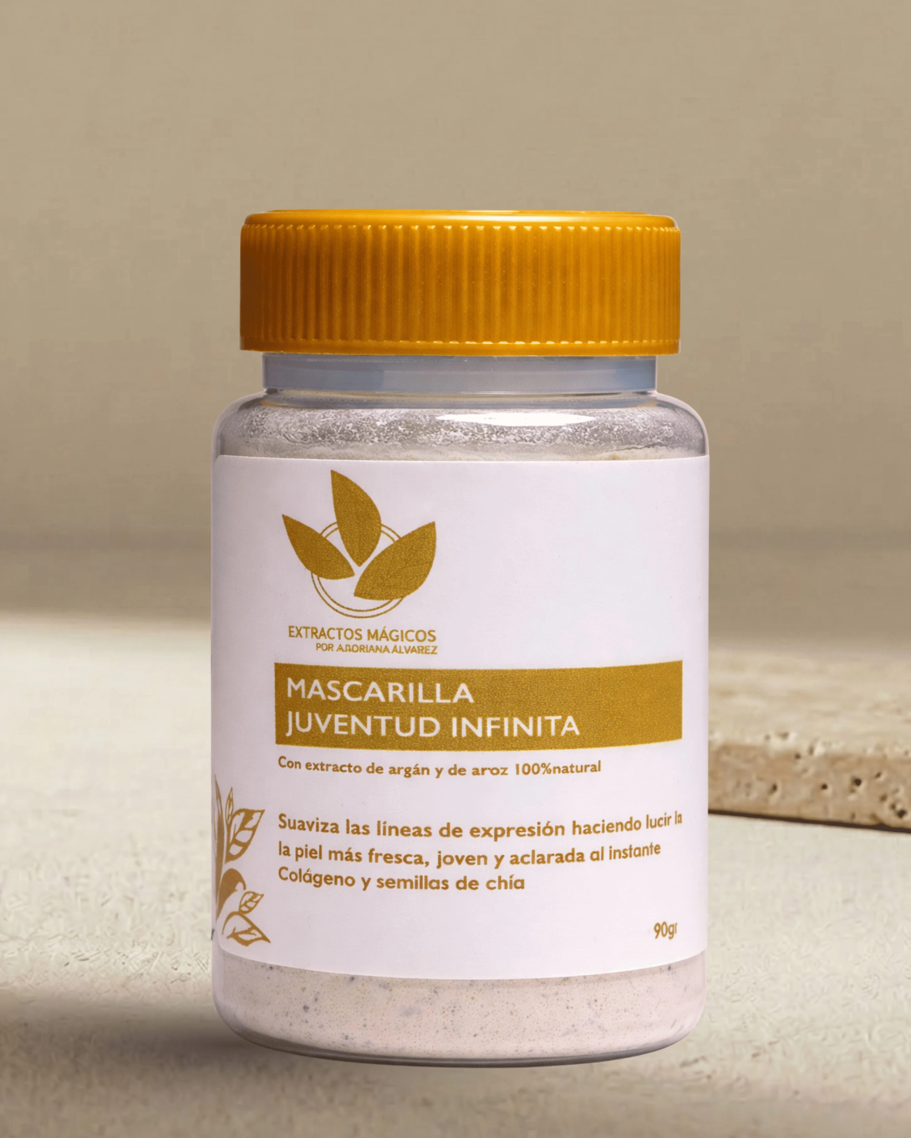 Botella de mascarilla facial en polvo con tapa amarilla, etiqueta blanca que muestra ingredientes naturales como argán y azafrán, y texto descriptivo sobre beneficios para la piel.