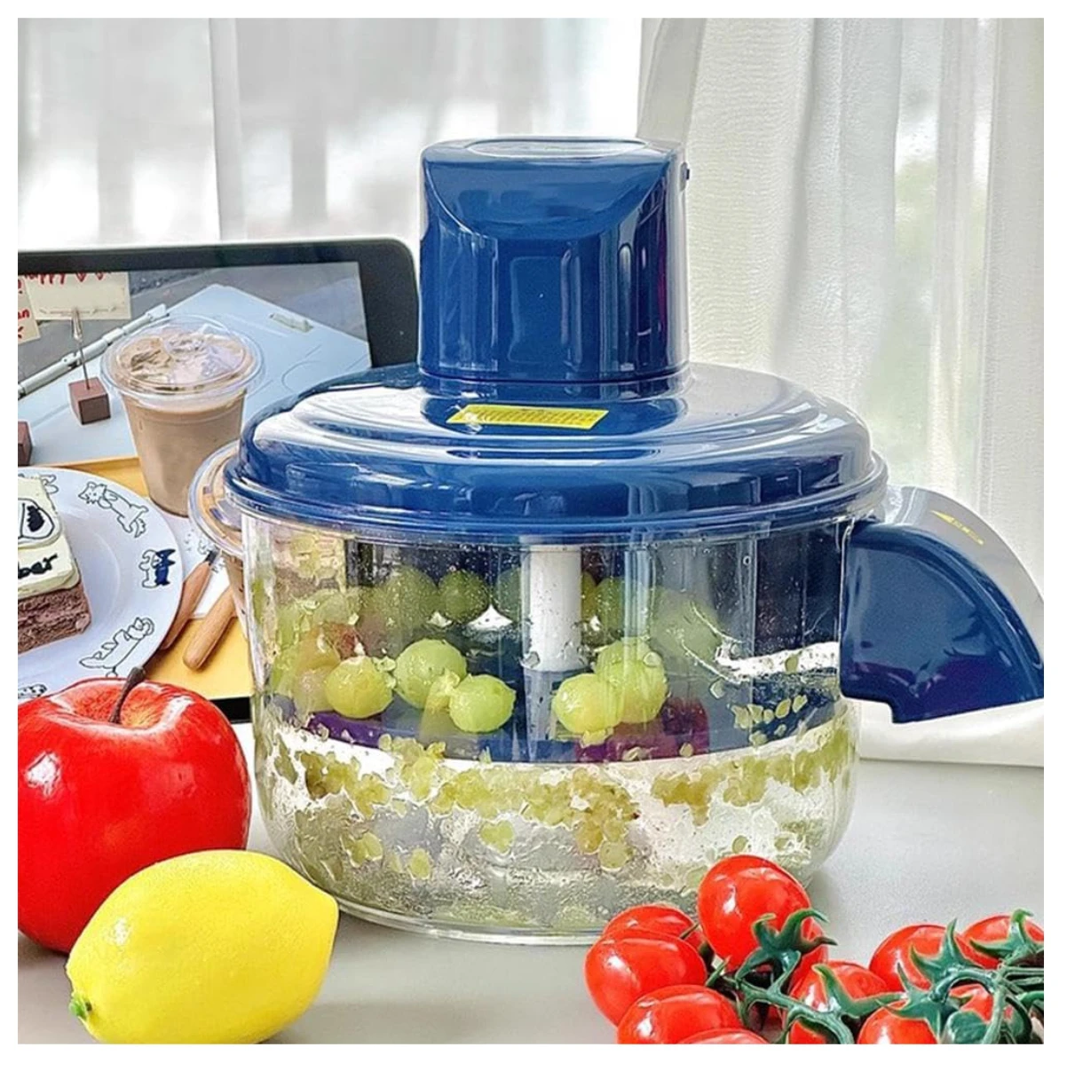Peladora automática de frutas y ajos inalámbrica en color azul, con mango ergonómico y base transparente que muestra uvas verdes y trozos de fruta procesada.