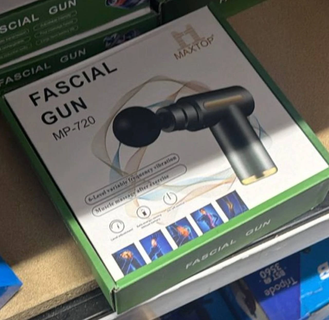 Caja del masajeador facial ergonómico Maxtop MP-720, color negro con detalles dorados, mostrando la herramienta y sus funciones en la parte frontal.