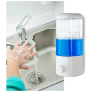 Dispensador de jabón líquido transparente con líquido azul, montado en pared junto a grifo de cocina; manos lavándose con espuma.