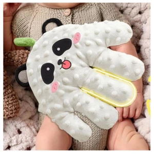 Almohada en forma de mano panda blanca con textura de puntos, orejas negras y detalles rosados, usada por bebé sobre manta. Incluye luz LED amarilla en la palma.