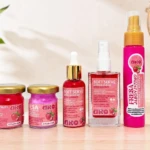 Kit de viaje con colágeno y jabón íntimo: cinco productos en presentaciones compactas, colores rosados y dorados, sobre superficie clara con fondo blanco y planta decorativa.