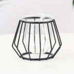 Macetero geométrico metálico negro con base de vidrio transparente, diseño minimalista para espacios modernos.