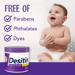Tubo de crema Desitin Máxima Protección Zinc, 454g, con etiqueta morada y texto blanco. Incluye iconos de "libre de parabenos, ftalatos y colorantes". Bebé sonriente sentado a la derecha.