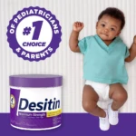 Tubito de crema Desitin Máxima Protección Zinc, color blanco con tapa morada, acompañado de bebé sonriente usando pañal y camiseta azul claro, sobre fondo liso con sello de aprobación de pediatras y padres.