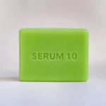 Jabón facial verde con la inscripción SERUM 10 en relieve, sobre fondo blanco. Presentación individual del producto.