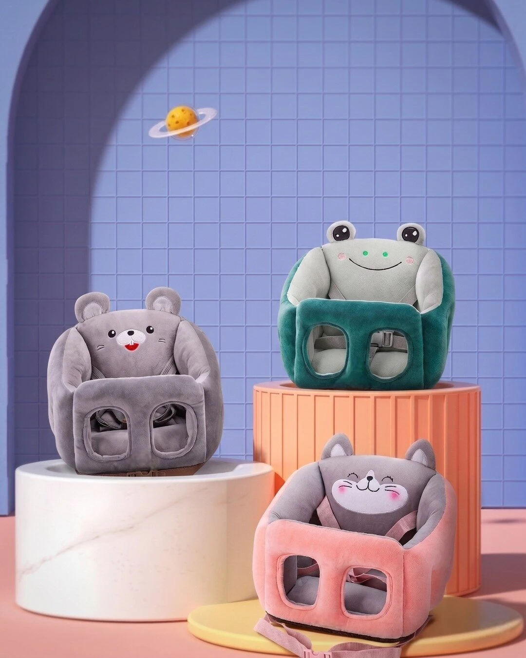 Tres sofás ergonómicos para bebé en colores gris, verde y rosa, con diseño de animales y cinturón de seguridad integrado, sobre pedestales decorativos.