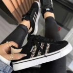 Zapatillas Adidas Campus para mujer, color negro con detalles en estampado animal print y suela blanca acolchada, vista desde arriba con usuario sosteniendo una unidad.